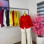Red textured floral lace button-down corporate shirt styled with cream wide-leg trousers