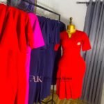Red short-sleeve corporate dress with gold brooch at the chest and a pleated hem