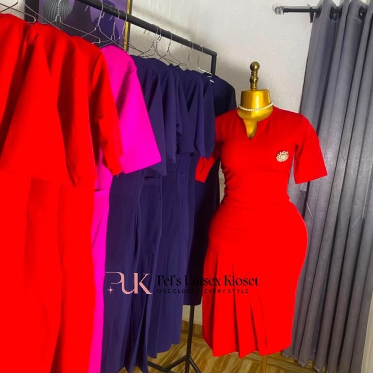 Red short-sleeve corporate dress with gold brooch at the chest and a pleated hem