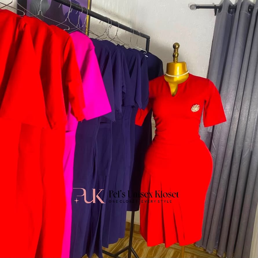 Women's Red Short-Sleeve Corporate Dress with Pleated Hem and Brooch Detail Red short-sleeve corporate dress with gold brooch at the chest and a pleated hem